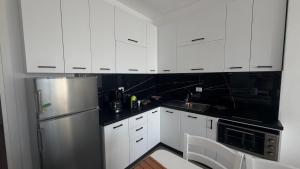 a kitchen with white cabinets and a stainless steel refrigerator at SoleMar Suites in Vlorë
