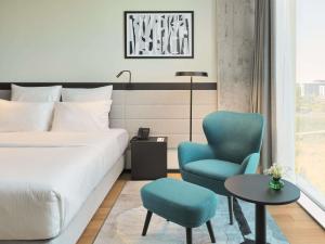 a hotel room with a bed and a chair at Pullman Zagreb in Zagreb