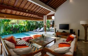 a living room with a couch and a table and a tv at Villa Vastu Seminyak in Seminyak