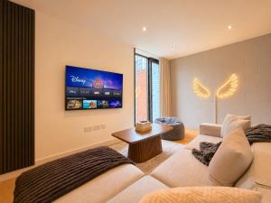 a living room with a couch and a flat screen tv at Luxury Townhouse 4BR I Roof Terrace I Free Parking in Manchester