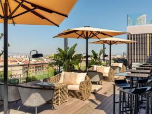 a rooftop patio with tables and chairs and umbrellas at Novotel Valencia Lavant in Valencia
