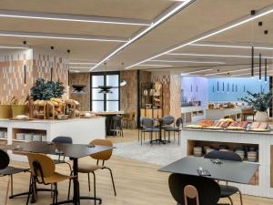 a restaurant with tables and chairs and a counter at Novotel Valencia Lavant in Valencia