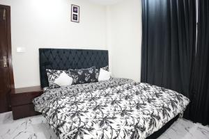 a bedroom with a bed with a black and white comforter at Royal Cottage in Murree in Murree