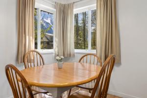 a dining room with a wooden table and chairs and windows at The Hitching Post Motel in Pemberton
