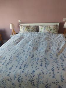 a bed with a blue and white blanket and pillows at Slievebawn Accommodation in Sligo +6 photos