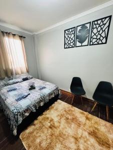 a bedroom with a bed and two chairs and a rug at Aeroporto de Guarulhos in Guarulhos