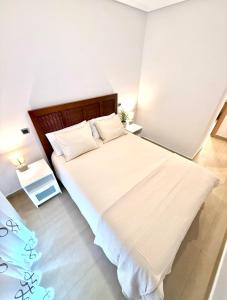 a bedroom with a large bed with white sheets and pillows at SunGolf Apartment in Los Alcázares