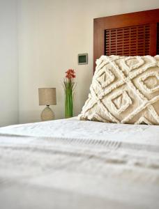 a white bed with a pillow and a vase of flowers at SunGolf Apartment in Los Alcázares
