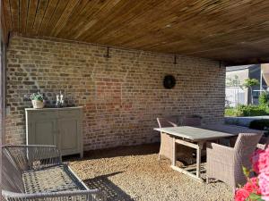 a patio with a table and chairs and a brick wall at Hoveke Paddebroek in Alveringem +14 photos