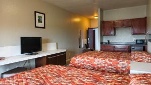 a hotel room with two beds and a flat screen tv at Studio 7 By Capital O Killeen I-14 in Harker Heights