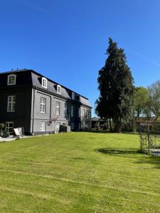 ein großes schwarzes Gebäude mit einem großen Rasenhof in der Unterkunft Brændte Ege Gods in Nykøbing Falster