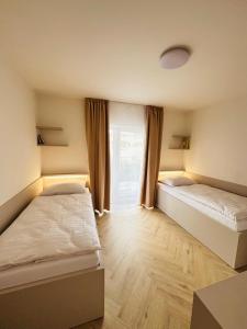 two beds in a room with a window at J&M apartman in Liptovská Teplá