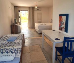 a room with two beds and a table and a desk at Vila Saguaro in Flecheiras