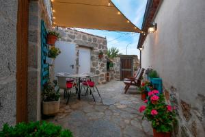 an outdoor patio with a table and chairs and flowers at Casa Rural El Berrueco in Robledillo