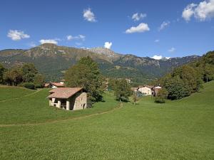 an old house in a field with mountains in the background at B&b Villa Giò in Cremeno