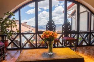 a vase with flowers on a table in front of a window at Tika Wasi Casa Boutique in Cusco