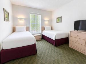 a hotel room with two beds and a flat screen tv at See you in Orlando in Kissimmee