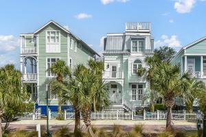 a green and white building with palm trees in front at Avonlea Cottage in Saint Simons Island