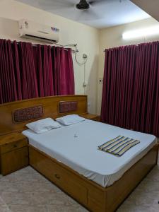 a bed in a room with red curtains at JUST WALKING DISTANCE FROM Temble in Guruvāyūr +6 photos