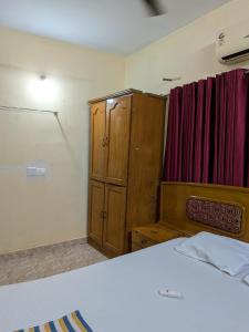 a bedroom with a bed and a wooden cabinet at JUST WALKING DISTANCE FROM Temble in Guruvāyūr