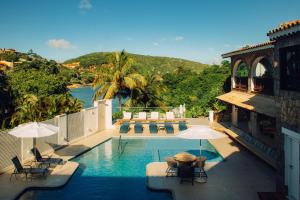 a swimming pool with chairs and umbrellas on a building at Colonna Park Hotel in Búzios