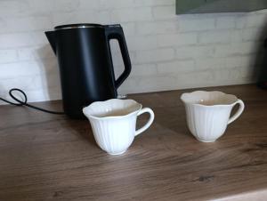 a black pitcher and two white cups on a table at Útulná Maringotka in Dolní Město