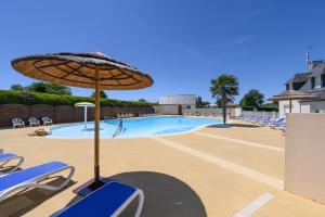 a swimming pool with an umbrella and lounge chairs at La Dune d’Erdeven in Erdeven
