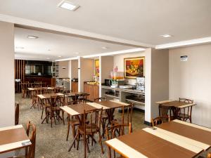 a restaurant with tables and chairs and a kitchen at Hotel Alvorada Taguatinga by Bsb Inn in Taguatinga
