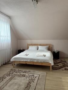 a bedroom with a bed with white sheets and a window at Barabás Guest House in Brădeşti