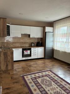 a kitchen with white cabinets and a refrigerator at Barabás Guest House in Brădeşti