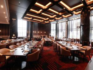 a dining room with tables and chairs and large windows at Novotel Sydney Cabramatta in Cabramatta