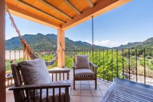 a porch with a hammock and chairs and a view at Casa rural en Terra Alta con vistas al Tossal d'Engrilló, cerca de la Vía Verde, espacios exteriores, doble barbacoa, ideal para familias, grupos y mascotas in Prat de Compte