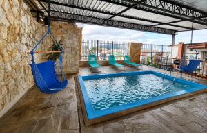a swimming pool with chairs and a swing at Hotel São Charbel in Ubatuba