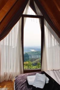 a bedroom with a large window with white curtains at Batllava Premium Resort Villa's in Orllan