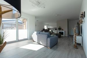 a living room with a blue couch and a living room with at Salz & Seele Das Spa Ferienhaus mit Whirlpool, Sauna & Wallbox in Büsum