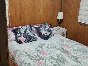 a bed with floral pillows on top of it at Cabaña La Petita in Cherquenco