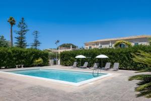 a swimming pool with chairs and umbrellas in a yard at Villa Aguglie Con Piscina in Modica