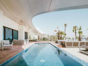 an indoor swimming pool with chairs and a building at Hawar Resort By Mantis in Hawar Island
