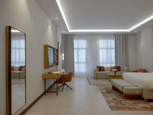 a hotel room with a bed and a living room at Mercure Hotel Khamis Mushait by Accor in Khamis Mushayt