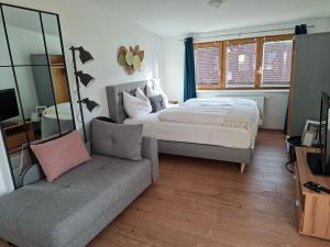 a bedroom with a bed and a couch at Lovely Rita Studio, modern Studio - balcony and mountain view - center Kaprun in Kaprun