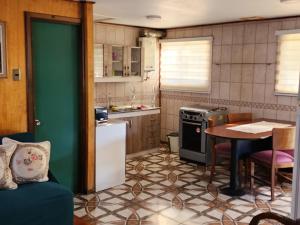 a small kitchen with a table and a refrigerator at Cabaña La Petita in Cherquenco