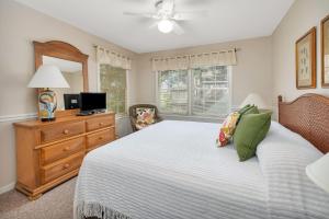 a bedroom with a bed and a dresser and a television at Oceanwood 109 in Saint Simons Island