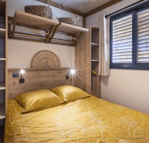 a bedroom with a bed with a yellow bedspread at Camping Le Boem in Balazuc