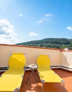 two yellow chairs and a table on a balcony at Airtegal Atico Mar de Cedeira in Cedeira