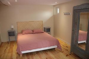 a bedroom with a bed with pink sheets and a mirror at Domaine de Calabel in Pouylebon