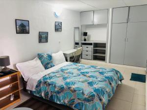a bedroom with a bed and a desk and a kitchen at Chambres d'hôtes WAIMEA in Abidjan