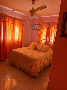 a bedroom with a bed with orange curtains and a fan at Mary Vilaseca in SJM