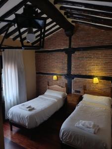 two beds in a room with a brick wall at Posada de Candelario in Candelario