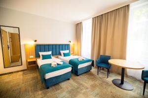 a hotel room with two beds and a table and chairs at Nysa Gubin in Gubin