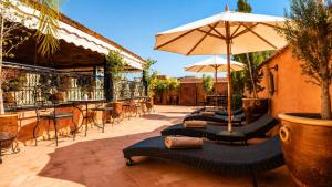 a patio with a row of chairs and an umbrella at Riad Medina Art & Suites in Marrakesh